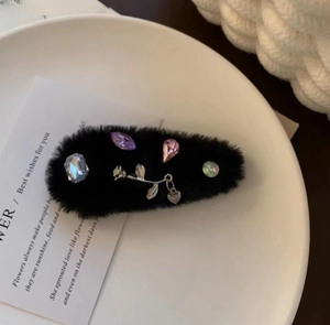 Detail of plush black headband featuring colorful rhinestones and silver rose motifs
