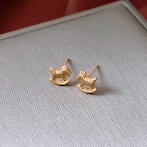 Polished 18K gold plated rocking horse stud earrings on a textured display box