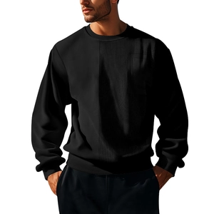 Detail shot of men's black sweatshirt featuring corduroy patchwork and a chest pocket