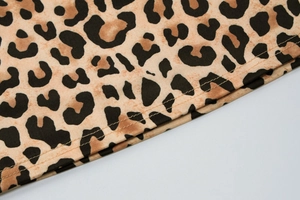 Detailed close-up of leopard print fabric featuring precise double-needle stitching hem