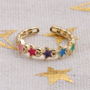 Close-up of gold-plated star rings with colorful enamel stars on white fabric