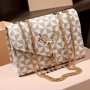Detail of the golden deer head lock and tassel on a geometric striped shoulder bag