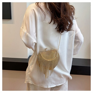 Model wearing a gold heart-shaped evening bag with crystal mesh and long tassels
