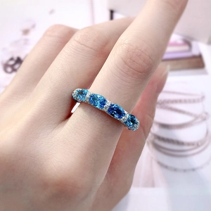 Macro shot of a 925 silver ring with blue oval gems and pavé crystals on a finger