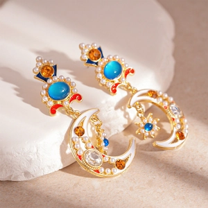 Vintage gold moon and star earrings with blue crystals and pearls on white stone base