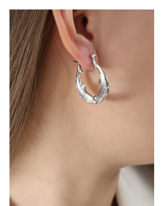 Close-up of a silver twist texture hoop earring showcasing intricate metal craftsmanship
