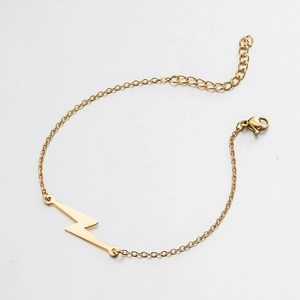 Detail view of a gold lightning bolt charm bracelet with adjustable lobster clasp closure
