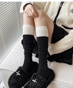 Detail showing black and white patchwork knit knee-high socks with ribbed cuffs texture