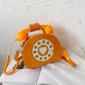 Detail of creative orange patent leather crossbody bag with vintage telephone handle