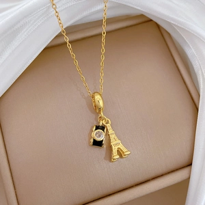 Detail view of gold titanium necklace with Eiffel Tower and black enamel camera pendant