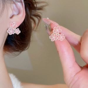 Gros plan sur les boucles d'oreilles fleur de cerisier en résine rose et métal doré