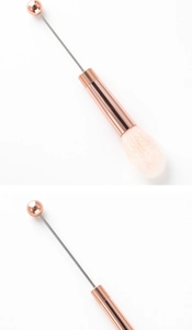 Detail of rose gold beadable makeup brush with soft pink and white synthetic bristles