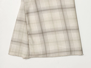 Macro shot of beige and grey plaid fabric texture with detailed overlock stitching