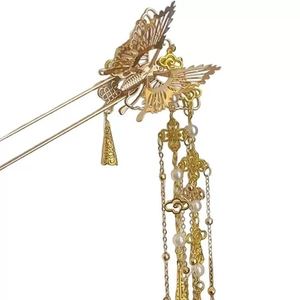 Close-up of golden butterfly hair pin with delicate metal tassels and white pearls
