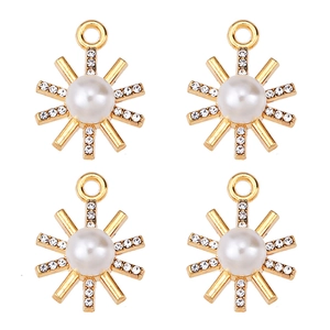 Detail of four golden sun pendants with pearl centers and zircon inlay on white background