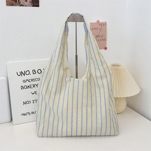Detailed macro view of yellow and blue striped canvas tote bag texture on display stand