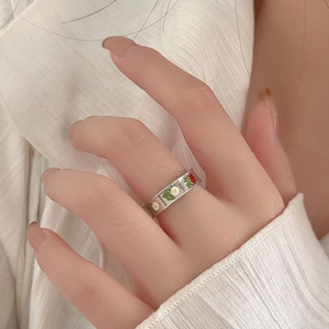 Detailed view of sterling silver daisy and leaf enamel ring worn on a person's hand
