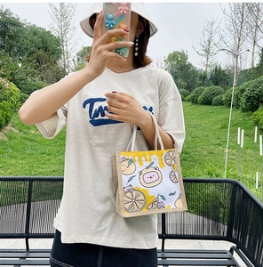 Detail of canvas tote bag featuring cute cartoon bear and lemon prints on woven texture