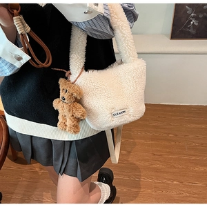 Détail du sac seau blanc en peau de mouton avec étiquette et breloque ours brun