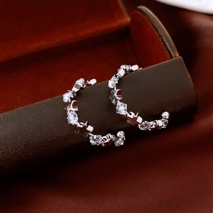 Detailed close-up of C-shaped silver hoop earrings with stars and sparkling zircons