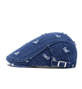 Side view of distressed dark blue denim flat cap with adjustable metal buckle buckle