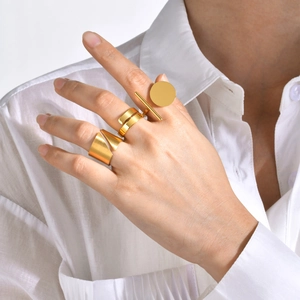 Detailed view of three minimalist geometric gold rings with brushed metal texture