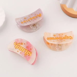 Three celestial marble hair claws in purple, peach, and pink with gold zodiac engraving
