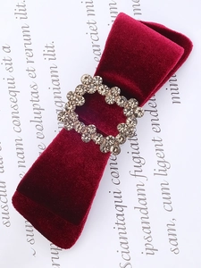Macro shot of burgundy velvet hair bow with sparkling square rhinestone buckle detail