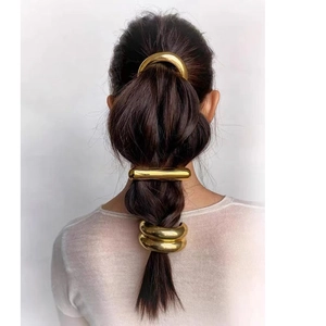 Detail of three minimalist gold metal hair clips styling a low ponytail for women