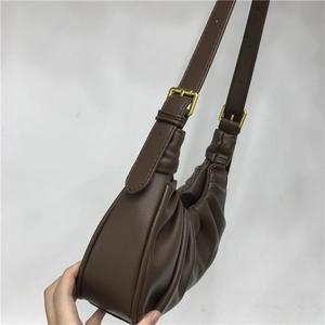 Detail view of the deep brown ruched cloud bag with adjustable strap and golden hardware