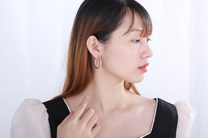 Silver hoop earrings with sparkling texture shown on model for realistic size reference