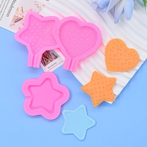 Close-up of star and heart silicone molds with finished resin crafts on blue background