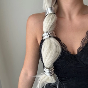 Detail view of silver metal ponytail cuffs with smooth and hammered textures on braided hair