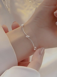 Detailed close-up of a minimalist silver beaded knot bracelet on a woman's wrist