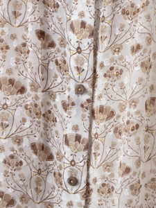 Détail du tissu en mousseline florale avec broderie délicate et petits boutons marron