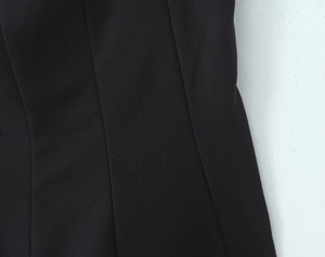 Dettaglio della trama in tessuto twill nero e cuciture di precisione sull'abito a collo alto