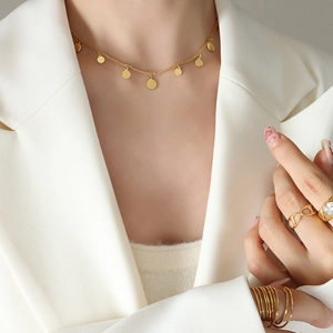 Minimalist gold disc pendant necklace and geometric rings set worn by a model