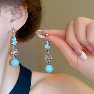 Detailed close-up of Bohemian silver earrings with sky blue stones and vintage floral patterns
