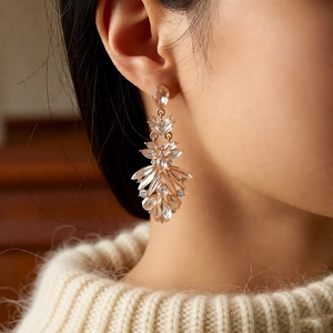 Detail of rose gold feather tassel earrings with champagne diamonds on model