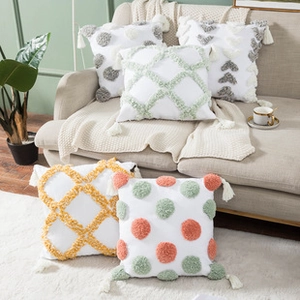 Detail view of tufted embroidered cushion covers with decorative fringes and tassels