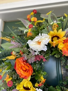 Close-up of a colorful summer wreath with eucalyptus and roses on a dark green door