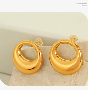 Detail view of gold organic curved earrings on a stone base with polished finish