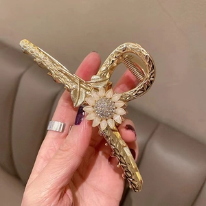 Detailed close-up of a golden sunflower hair claw with white opal petals and rhinestones