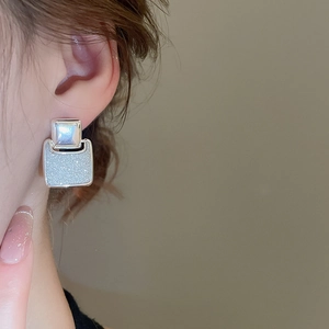 Close-up of elegant silver square drop earrings with textured finish worn by a model