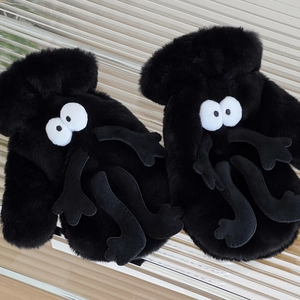 Detailed close-up of plush black soot sprite gloves featuring large white eyes and fuzzy limbs