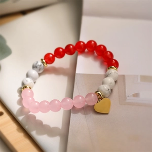 Detailed close-up of beaded bracelet with red agate, pink quartz and heart charm