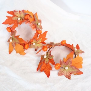 Detail of autumn candle rings featuring orange maple leaves, mini pumpkins and pearls