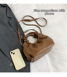 Brown ruched cloud bag size comparison with a smartphone showing compact proportions