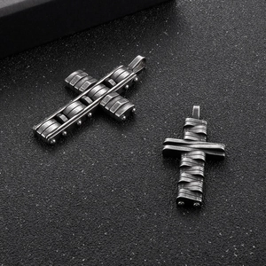 Detailed view of two hip-hop style black stainless steel cross pendants on matte background