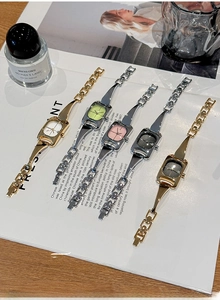 Close-up of five luxury women's square watches with metal link straps on a magazine
